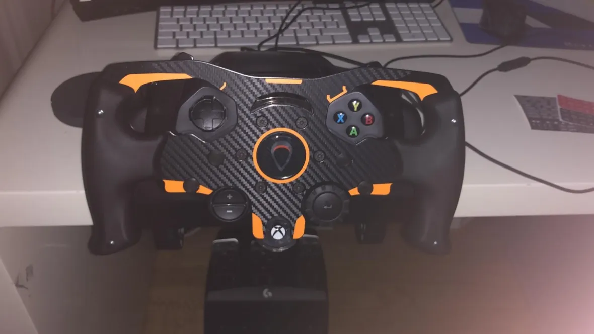 A cheap sim wheel clamped to a desk in 2020