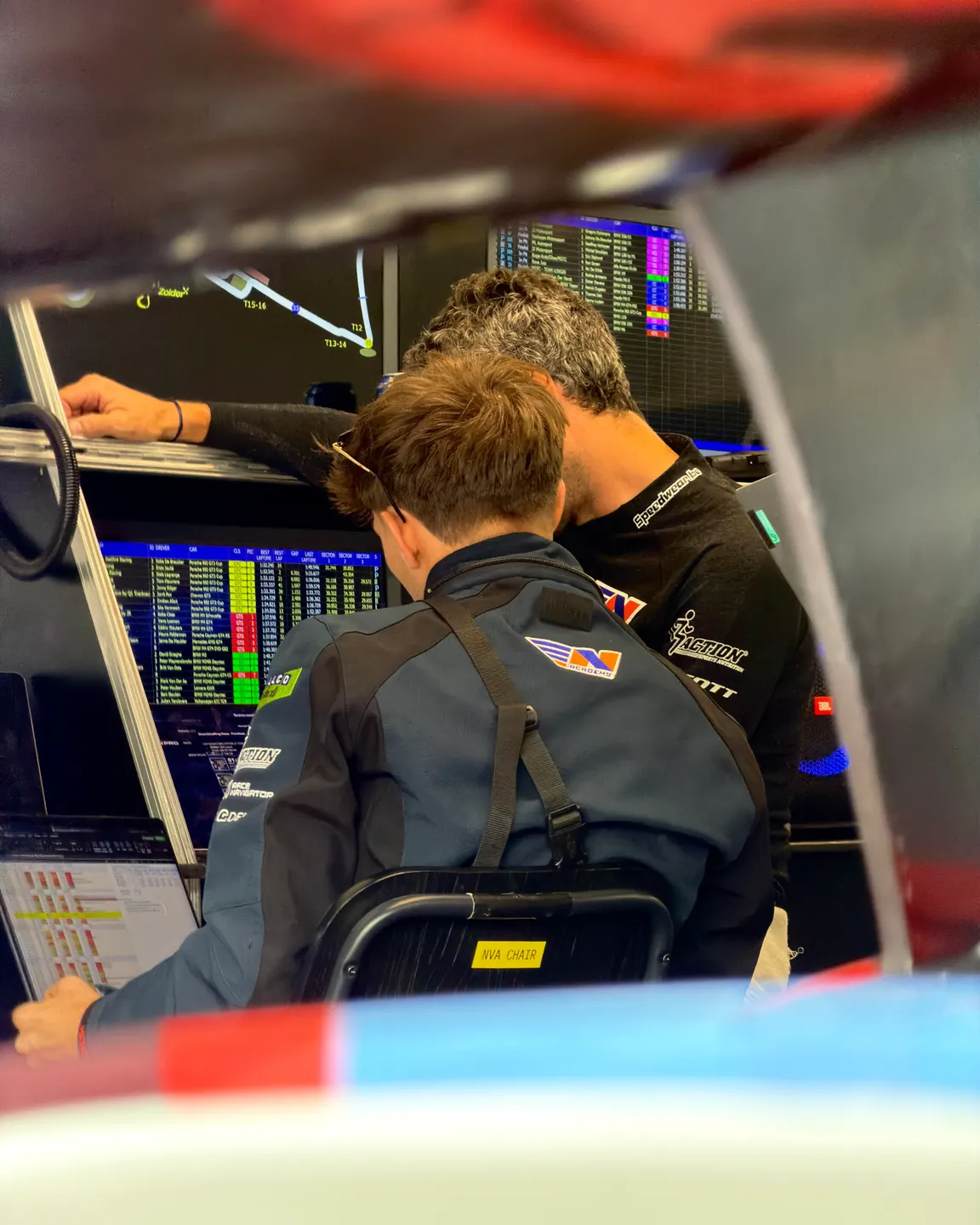 Coaching at the pit wall in Zolder, two people bent over the timing screens and the telemetry